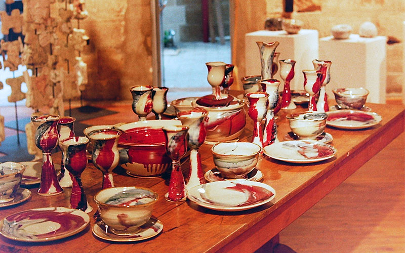 Ceramics banquet with vivid red brushwork displayed in cellblock theatre at National Art School